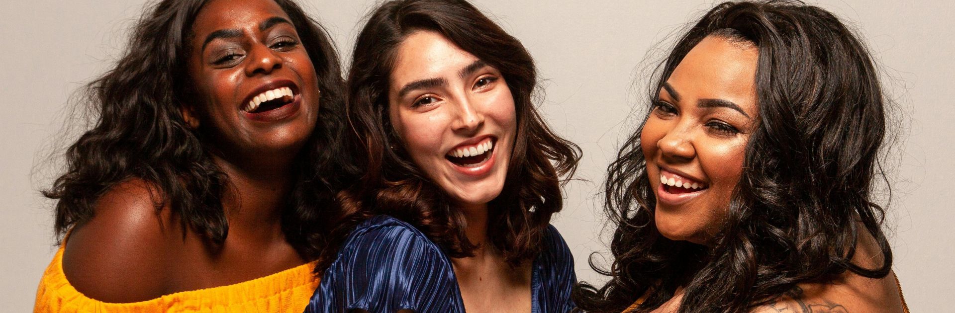 Joyful group of diverse women laughing together in bright outfits.